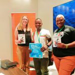 A picture of FIFAfrica24 panelist holding copies of Best Practices For Digital Inclusion of People With Disability In Kenyan Community Networks.