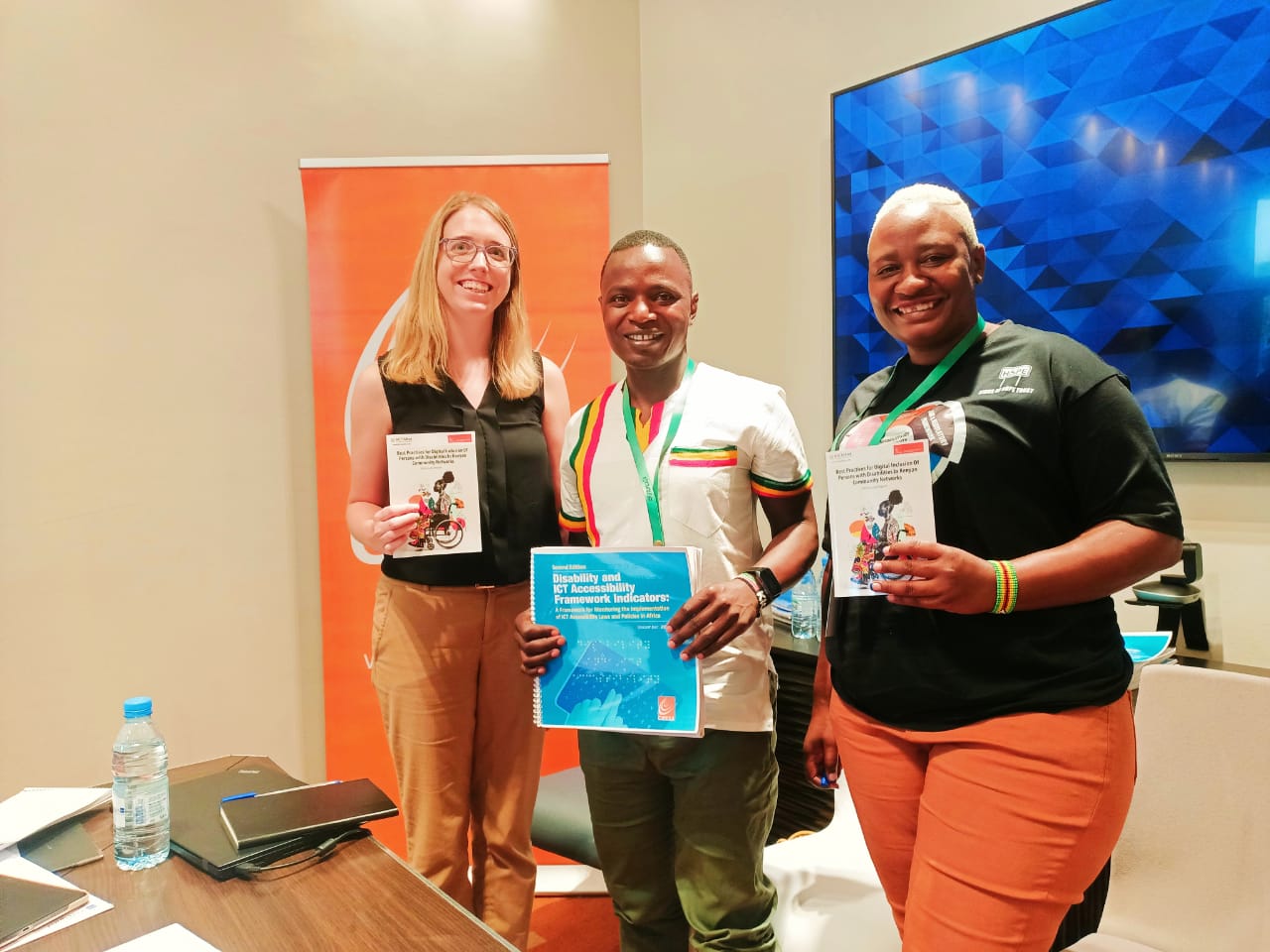 A picture of FIFAfrica24 panelist holding copies of Best Practices For Digital Inclusion of People With Disability In Kenyan Community Networks.