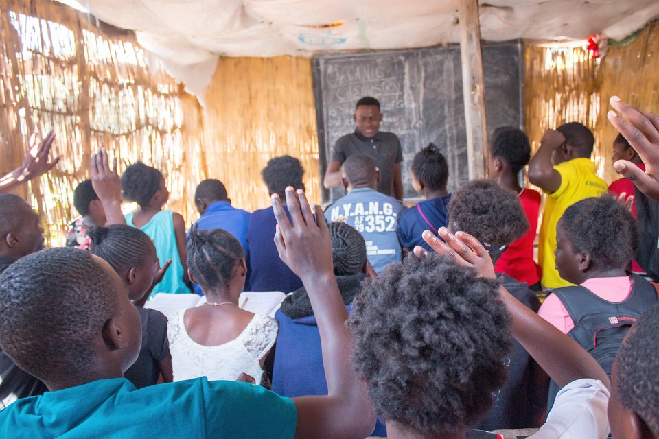 A photo of individuals raising hands while facing away from the camera