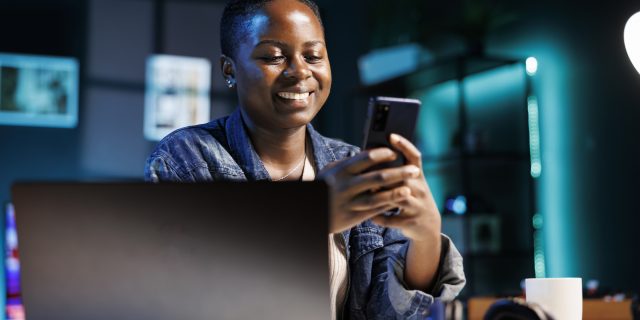 A female students using mobile device with a laptop in the foreground