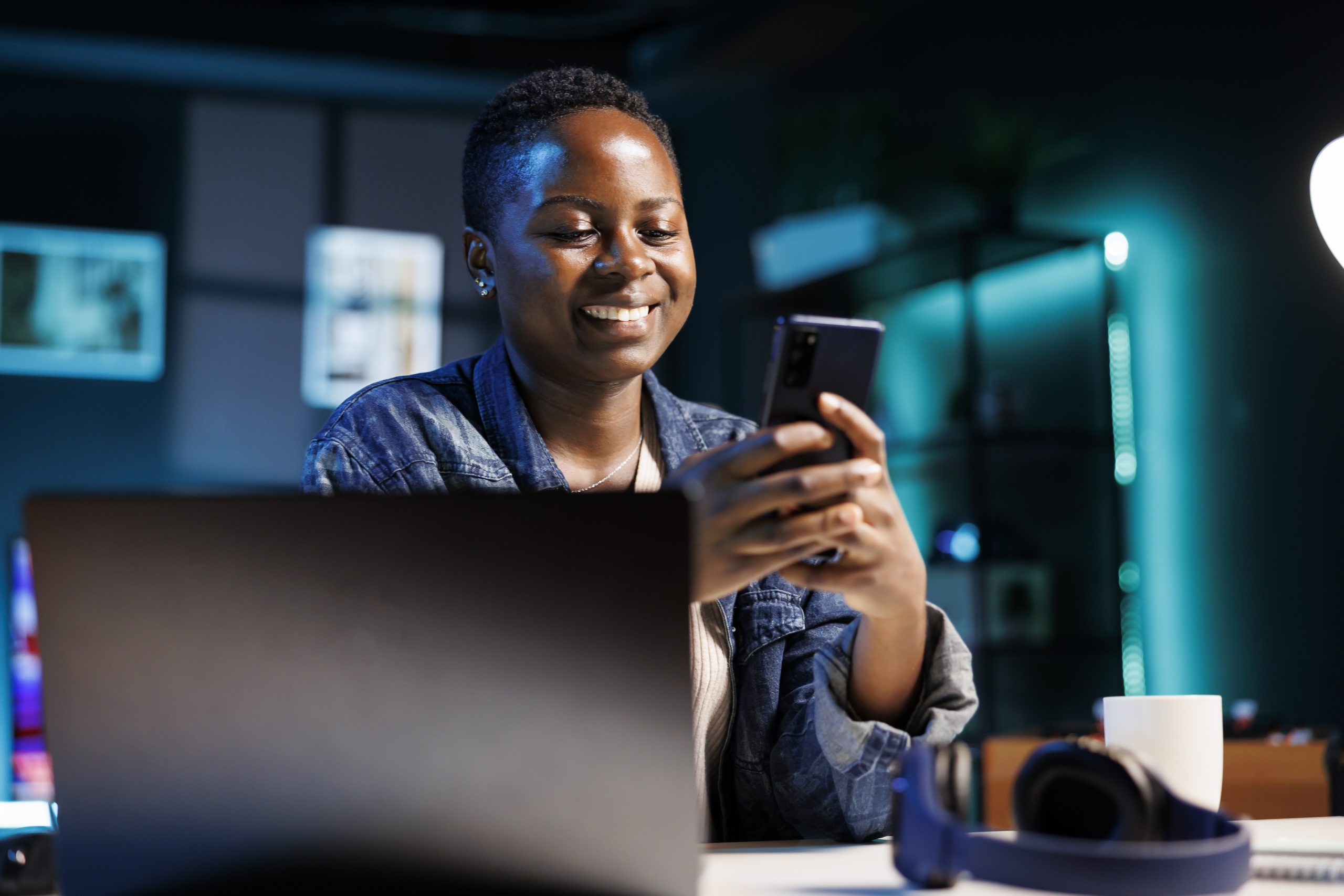 A female students using mobile device with a laptop in the foreground